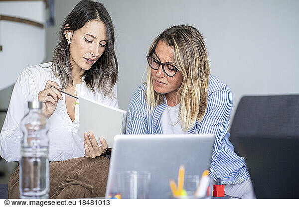 Businesswoman discussing with colleague over book at home office