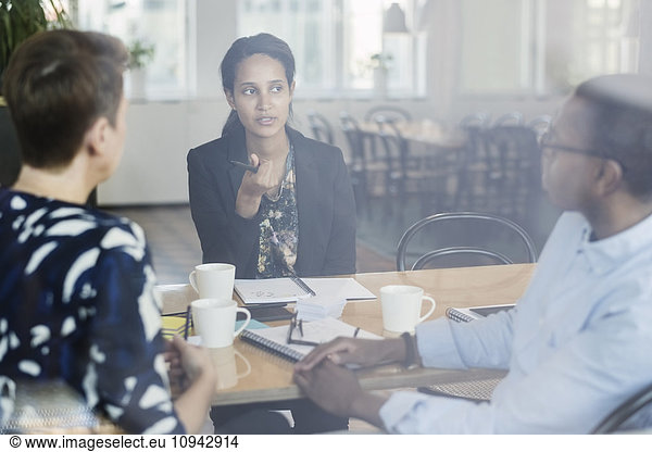 Businesswoman discussing with colleagues at conference table