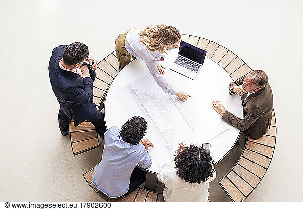 Businesswoman discussing with colleagues over document on table in corridor