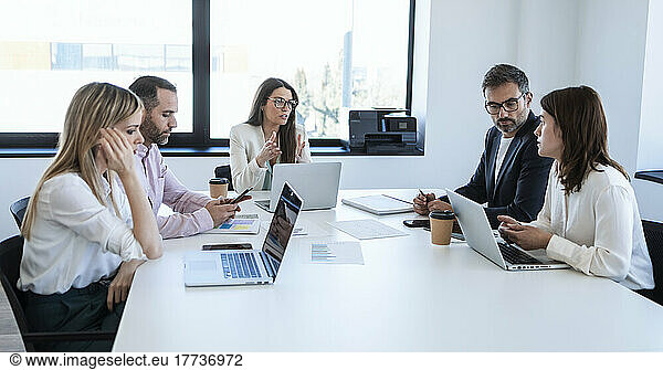 Businesswoman discussing with colleagues sitting in boardroom at office