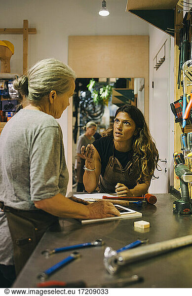 Businesswoman discussing with female colleague in bicycle workshop