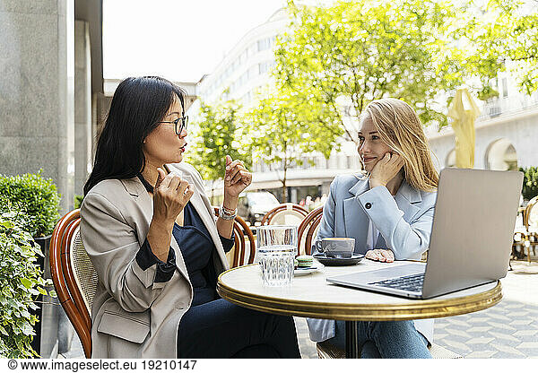 Businesswoman discussing with partner at sidewalk cafe