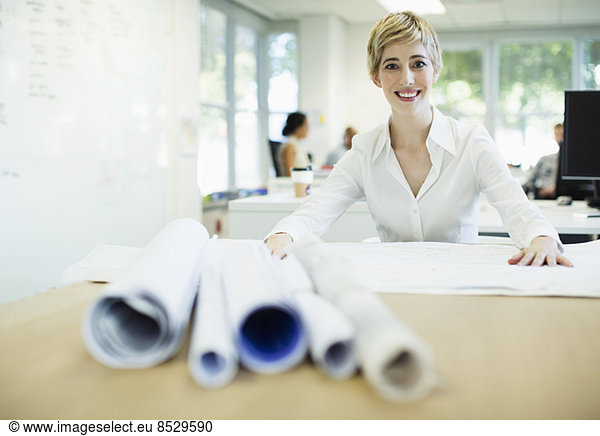 Businesswoman examining blueprints in office