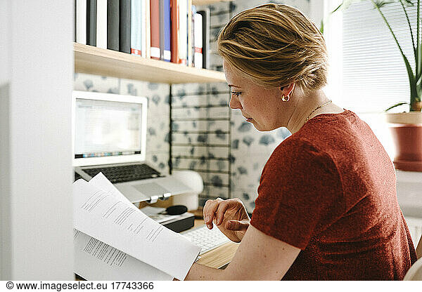 Businesswoman examining documents at desk during work from home