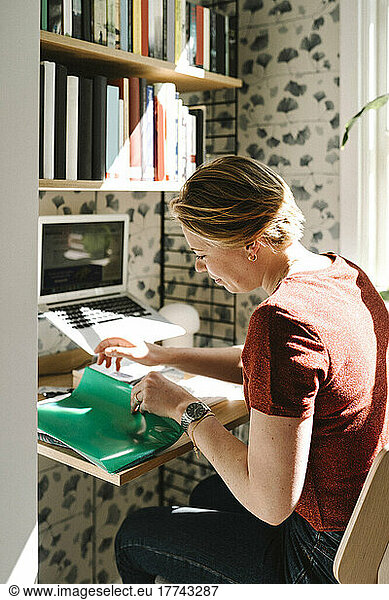 Businesswoman examining file at desk during work from home