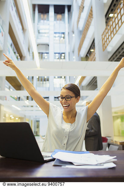 Businesswoman excited while working in office building