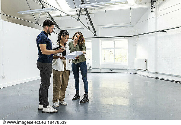 Businesswoman explaining blue print to colleagues in empty space