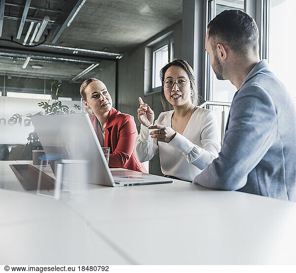 Businesswoman explaining colleagues through gestures in meeting at office