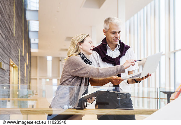Businesswoman explaining strategy to colleague on laptop at hotel lobby