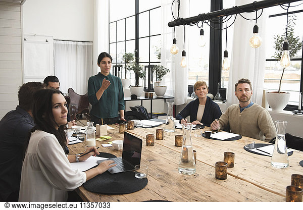 Businesswoman explaining to colleagues during meeting at table in office