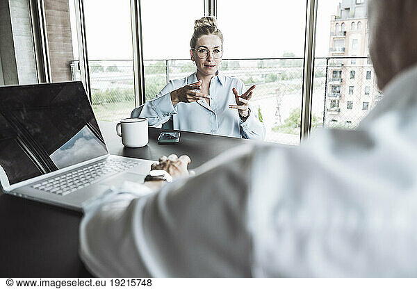 Businesswoman gesturing and discussing with colleague in office