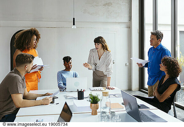 Businesswoman gesturing and discussing with colleagues in meeting