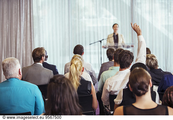 Businesswoman giving presentation in conference room  people raising hands