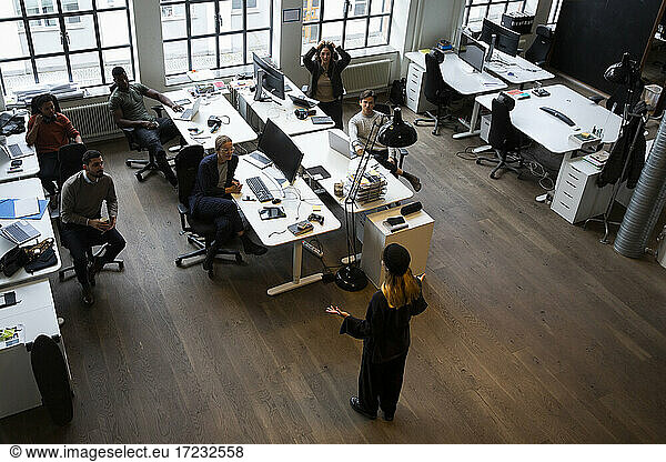Businesswoman giving presentation to colleagues during meeting at creative office