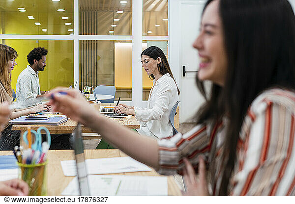 Businesswoman handing over pen to colleague in office