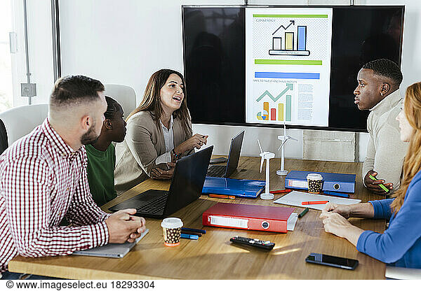 Businesswoman having discussion with colleagues over renewable energies in meeting at office