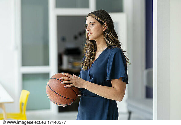 Businesswoman holding basketball in office