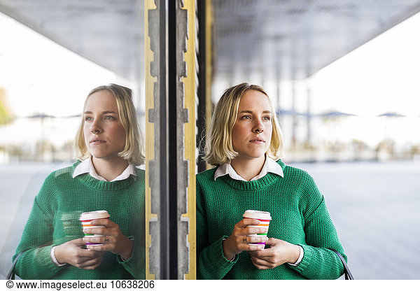 Businesswoman holding coffee cup while looking away outdoors