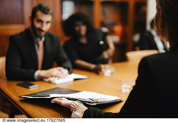 Businesswoman holding contract document discussing with financial advisors in meeting