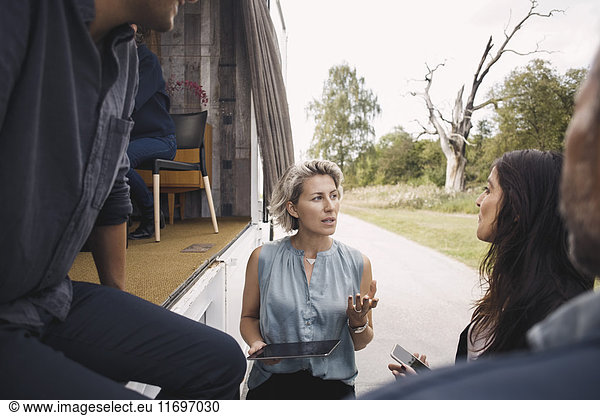 Businesswoman holding digital tablet while discussing with colleagues by portable office truck
