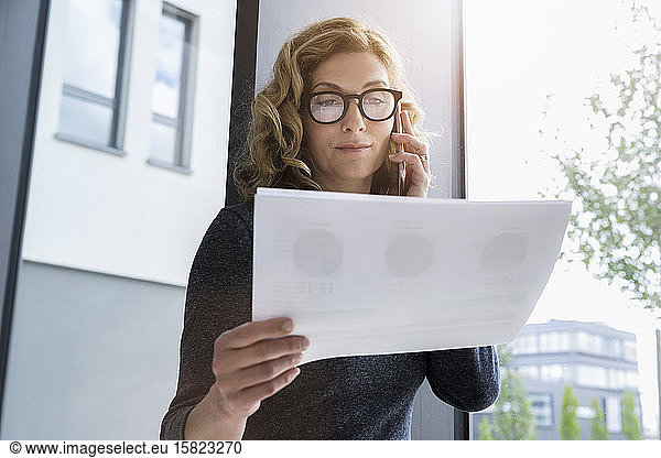 Businesswoman holding documents and calling at the office