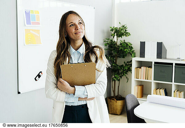 Businesswoman holding file folder standing in front of white board