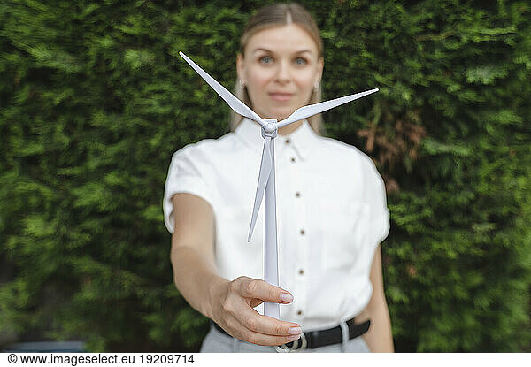 Businesswoman holding model wind turbine