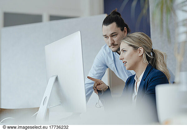 Businesswoman in meeting with colleague pointing at desktop PC
