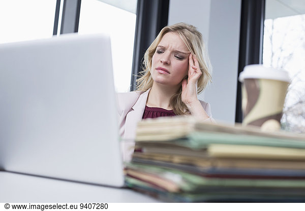 Businesswoman in office with headache