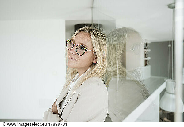 Businesswoman leaning against glass wall in office