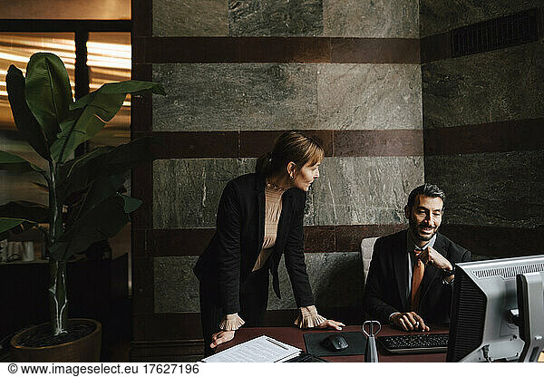 Businesswoman leaning on desk discussing with businessman at law office