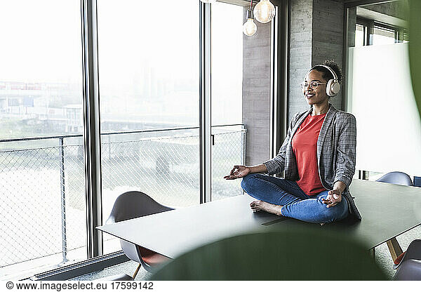 Businesswoman listening music and meditating at work place