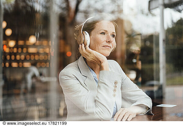 Businesswoman listening music through wireless headphones in cafe