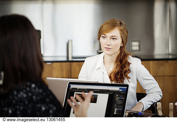 Businesswoman looking at colleague while having discussion in office