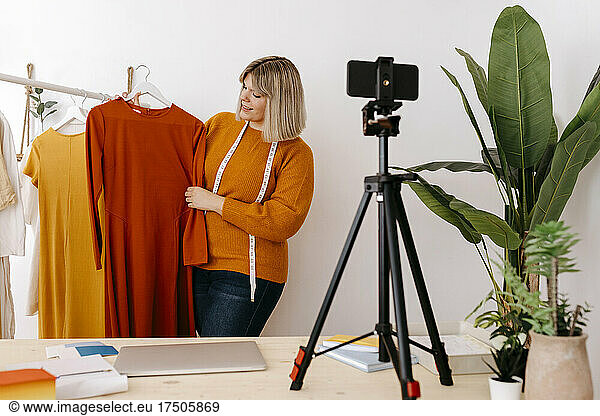Businesswoman looking at dress doing video call at creative office