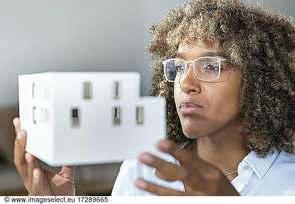 Businesswoman looking at house model while working at office