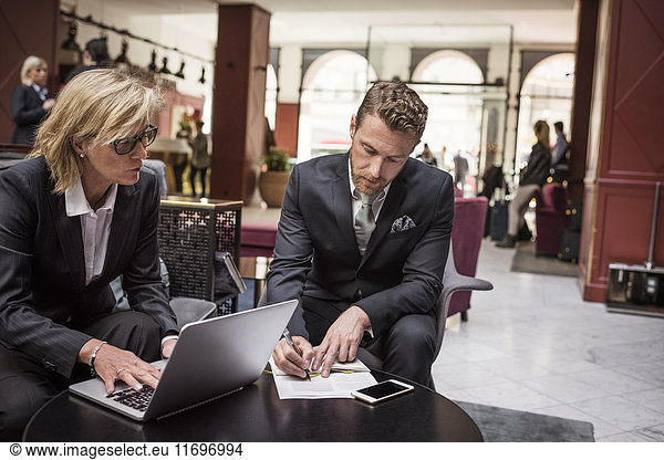 Businesswoman looking at partner signing agreement in hotel reception