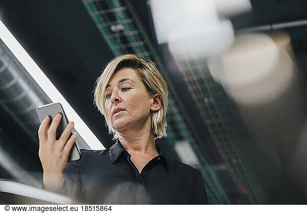 Businesswoman looking at smart phone in office