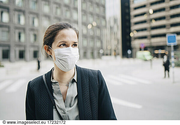 Businesswoman looking away on street in city during pandemic
