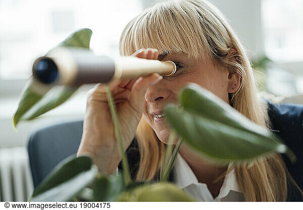 Businesswoman looking through hand-held telescope