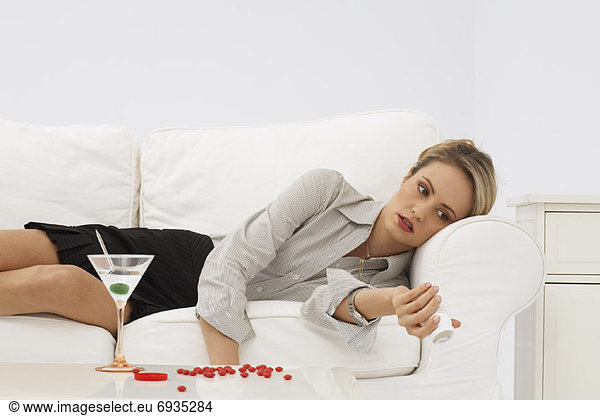 Businesswoman Lying on Sofa  with Pills and Martini