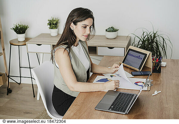 Businesswoman making notes from laptop in office