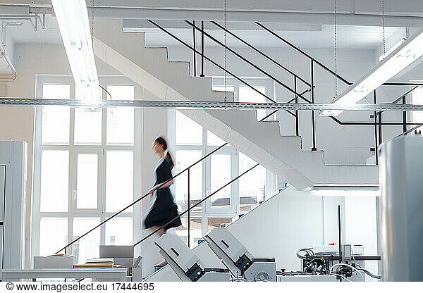Businesswoman moving down on staircase in workshop