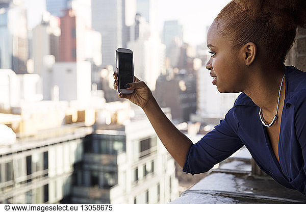 Businesswoman photographing city through smart phone