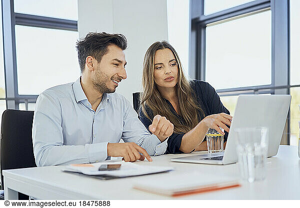 Businesswoman planning strategy with colleague over laptop at workplace