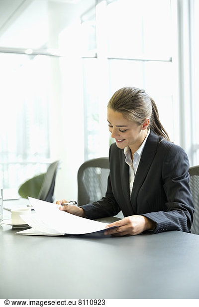 Businesswoman reading paperwork in conference room