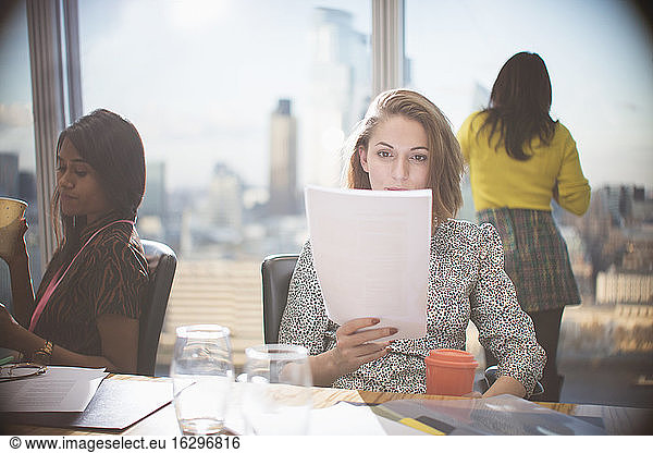 Businesswoman reading paperwork in conference room meeting