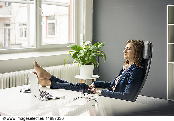 Businesswoman relaxing in office with feet up