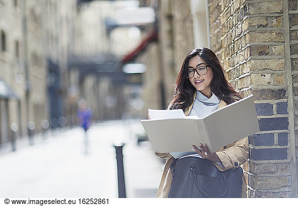 Businesswoman reviewing paperwork on sunny city street