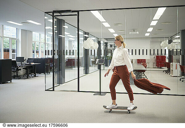 Businesswoman riding on skateboard in office